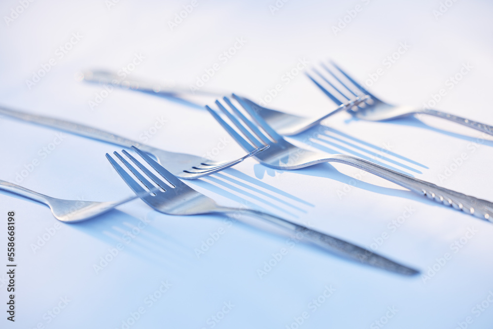 Fork, cutlery and symmetry with eating utensils on a table in an empty studio on a blue background from above. Kitchen, utensil and forks closeup ready for breakfast, lunch or dinner in a restaurant Fork, cutlery and symmetry with eating utensils on a table in an empty studio on a blue background from above. Kitchen, utensil and forks closeup ready for breakfast, lunch or dinner in a restaurant