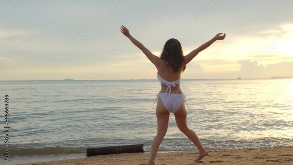 Back view, Young beautiful woman wear bikini swimsuit walking tropical beach and raise hand for freedom at golden sunset, Happy Asian female relaxing in holiday outside sunset, Summer travel vacation Back view, Young beautiful woman wear bikini swimsuit walking tropical beach and raise hand for freedom at golden sunset, Happy Asian female relaxing in holiday outside sunset, Summer travel vacation