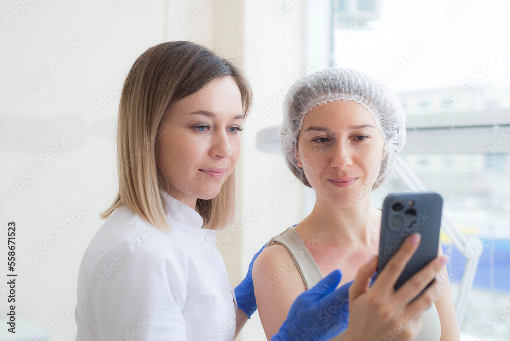 Fototapeta premium Cosmetologyst and model making looking at mabile phone in spa salon.