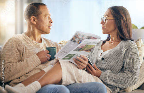 Senior couple, newspaper and relax talking on sofa reading, morning conversation or quality time bonding together in living room. Elderly man, woman and news discussion, coffee and retirement peace