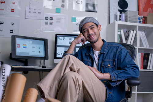 Portrait of Asian man graphic designer sitting and smiling while looking at camera.