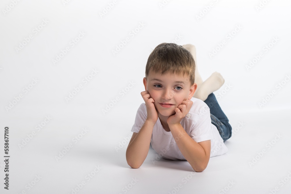 a little boy of European appearance on a white background lies on the floor a little boy of European appearance on a white background lies on the floor