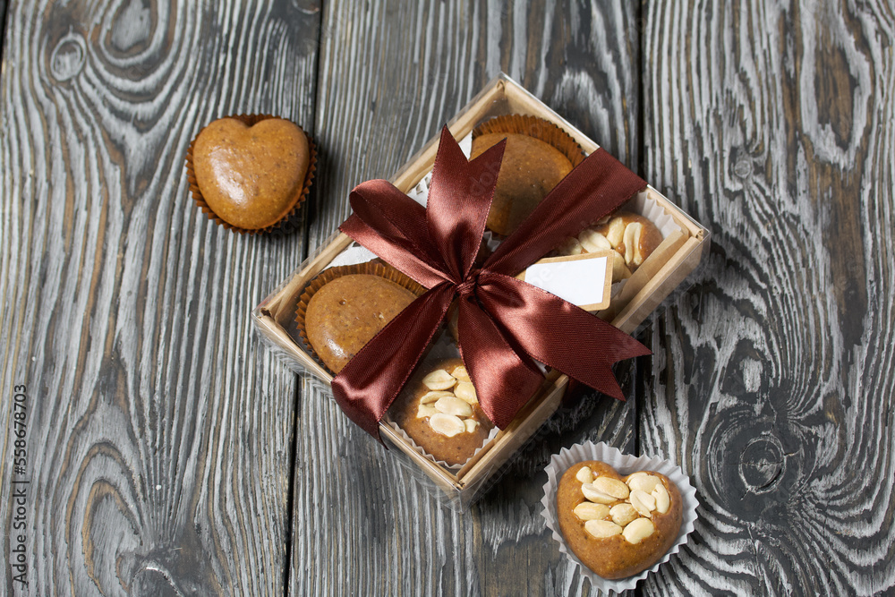 Homemade caramel. Brown caramel candies. Creamy sweets with peanuts. On pine boards. Some of them are packed in a box and tied with a ribbon.