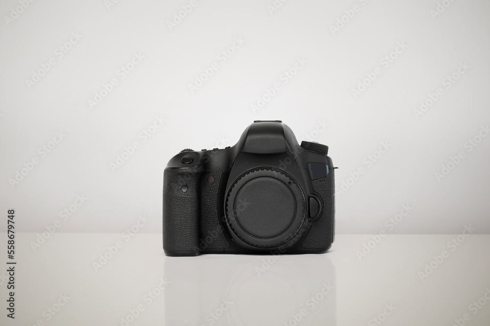 Camera isolated on a white background. The camera is placed on a glossy surface that reflects the shape of the camera