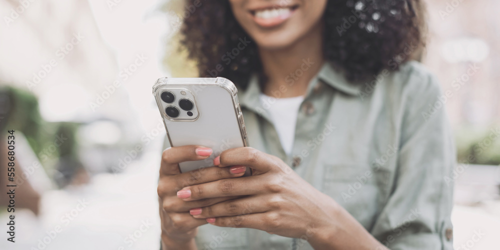 Fototapeta premium Young woman using smartphone in a city. Student girl texting on mobile phone outdoor panoramic banner. Communication, connection, mobile apps, technology, lifestyle concept