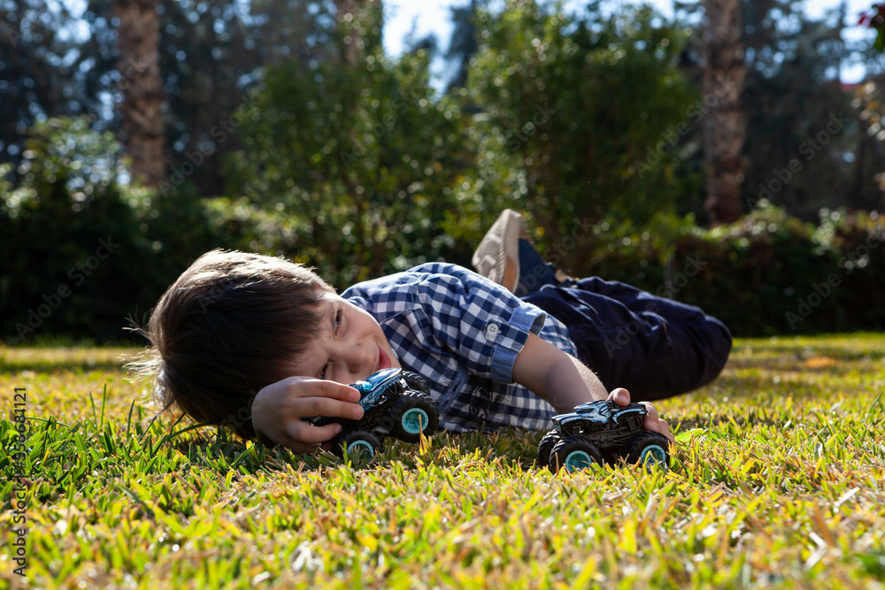 Boy is playing a cars multitrack on the garden 