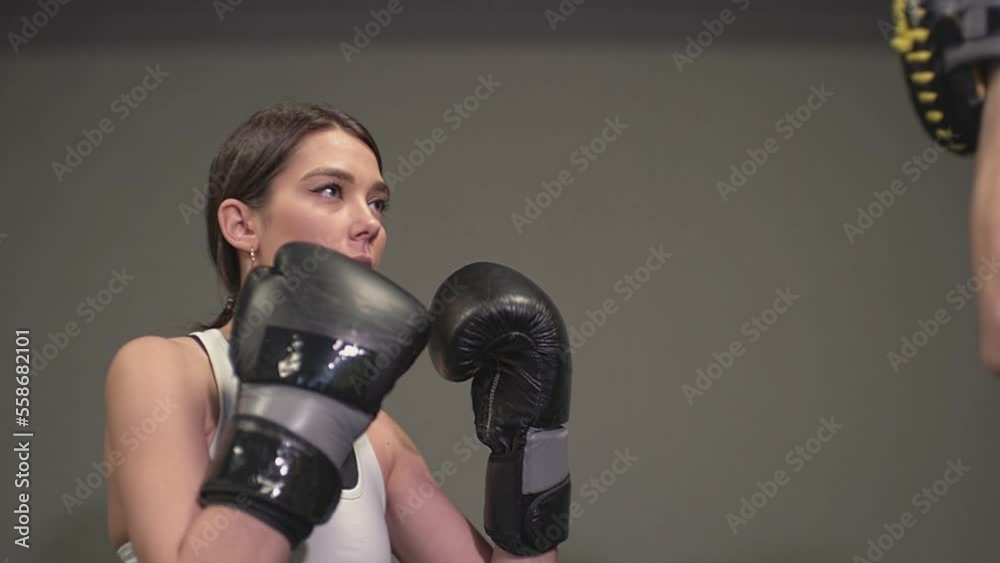 a man in a gray gym trains a girl with punches on the paw for boxing. High quality Full HD video recording a man in a gray gym trains a girl with punches on the paw for boxing. High quality Full HD video recording