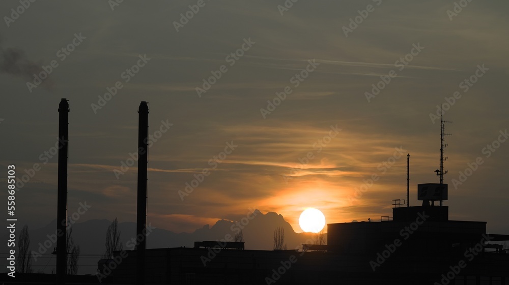 Sun sets behind an industrial building