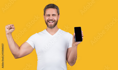 happy man showing phone screen in studio. man showing screen of phone.