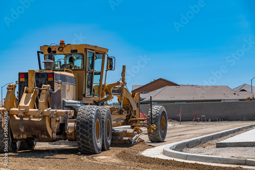 Yellow excavator, road repair. Rear view. Blue sky background.