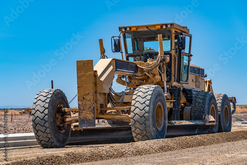 Yellow excavator, road repair. Close-up. Blue sky background.