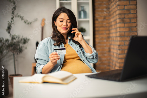 Pregnant woman shopping online at home. Happy woman with laptop and credit card.