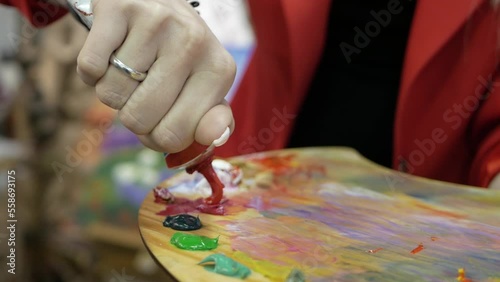 Art preparation. Painting process. Female artist squeezing colorful paints from tubes on palette in mess tools table