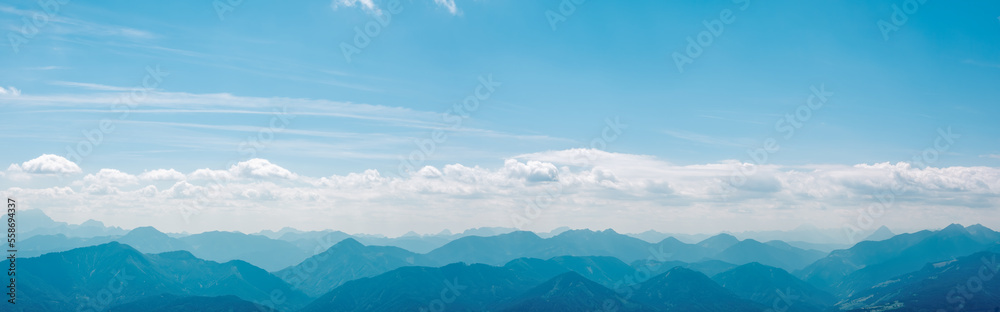 A panorama of successive high mountain ranges on the horizon. High peaks covered with clouds, blue sky in the background, Austrian Alps.