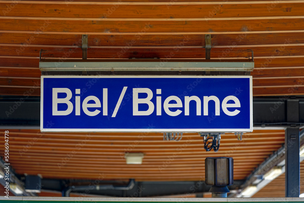 Blue and white sign at wooden ceiling of platform roof on a sunny autumn day. Photo taken November 10th, 2022, Biel Bienne, Switzerland.