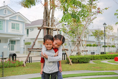 Obraz na płótnie Happy family of Asian sister hugging her little brother in the garden