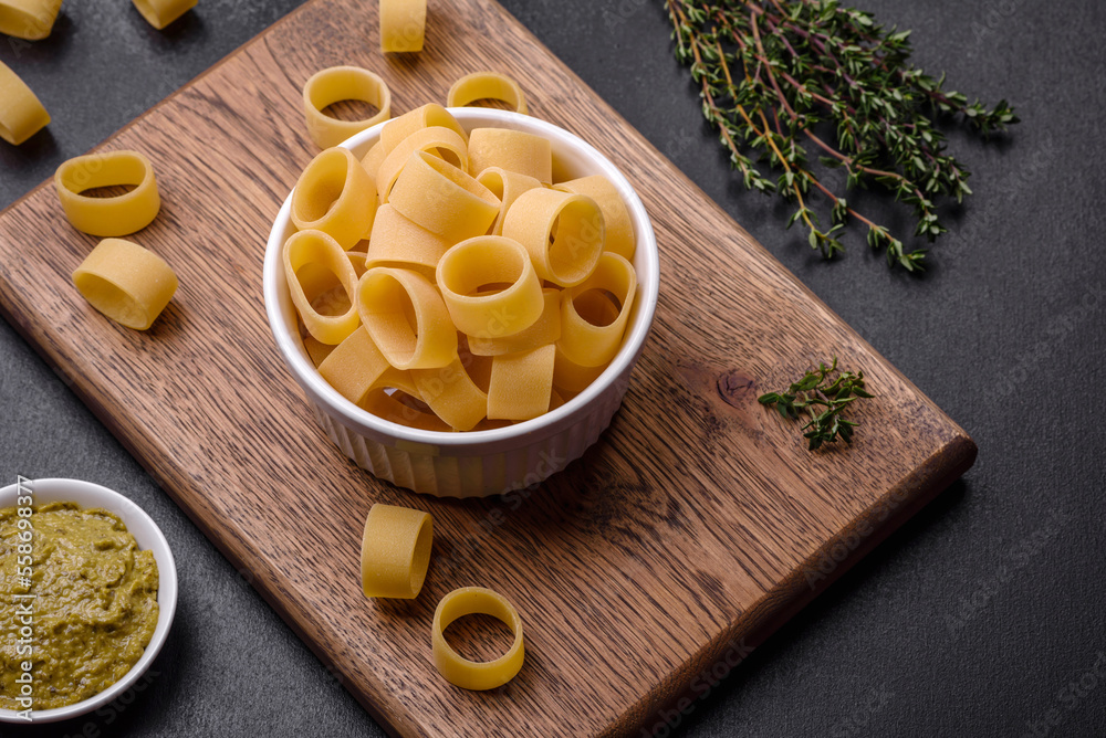 Raw uncooked pasta in a white ceramic bowl with spices and herbs Raw uncooked pasta in a white ceramic bowl with spices and herbs