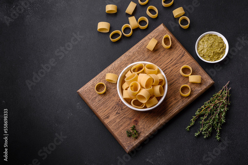 Raw uncooked pasta in a white ceramic bowl with spices and herbs