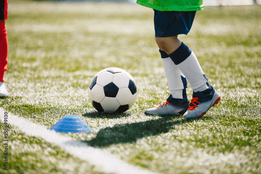 Obraz premium Little boy running and kicking classic soccer ball on training class