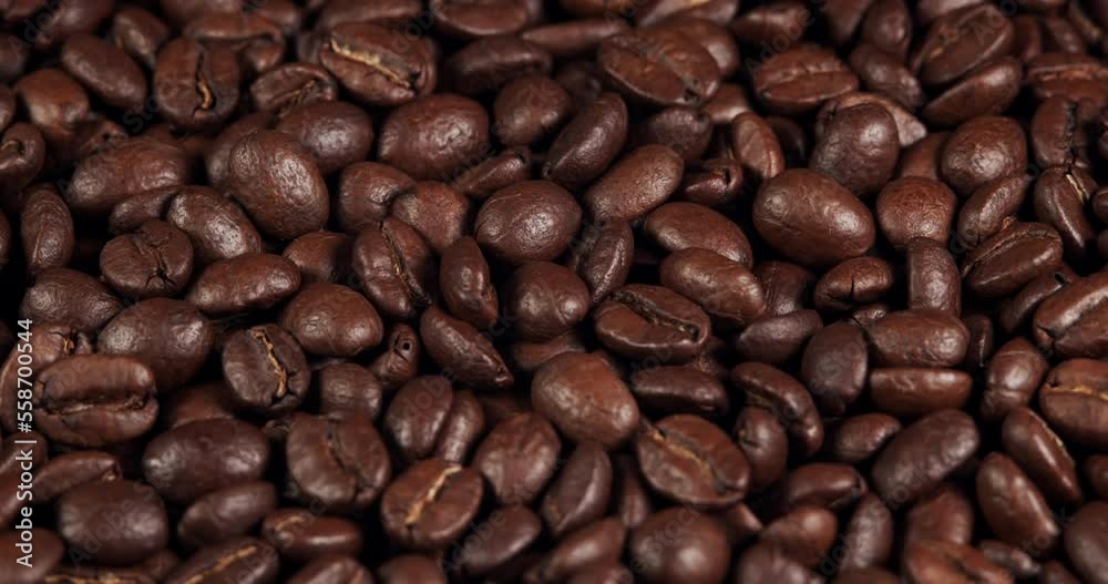 Roasted coffee beans dolly shot. Aromatic coffee beans move slowly. Slide slow motion close-up of whole roasted coffee beans. Roasted coffee beans dolly shot. Aromatic coffee beans move slowly. Slide slow motion close-up of whole roasted coffee beans.