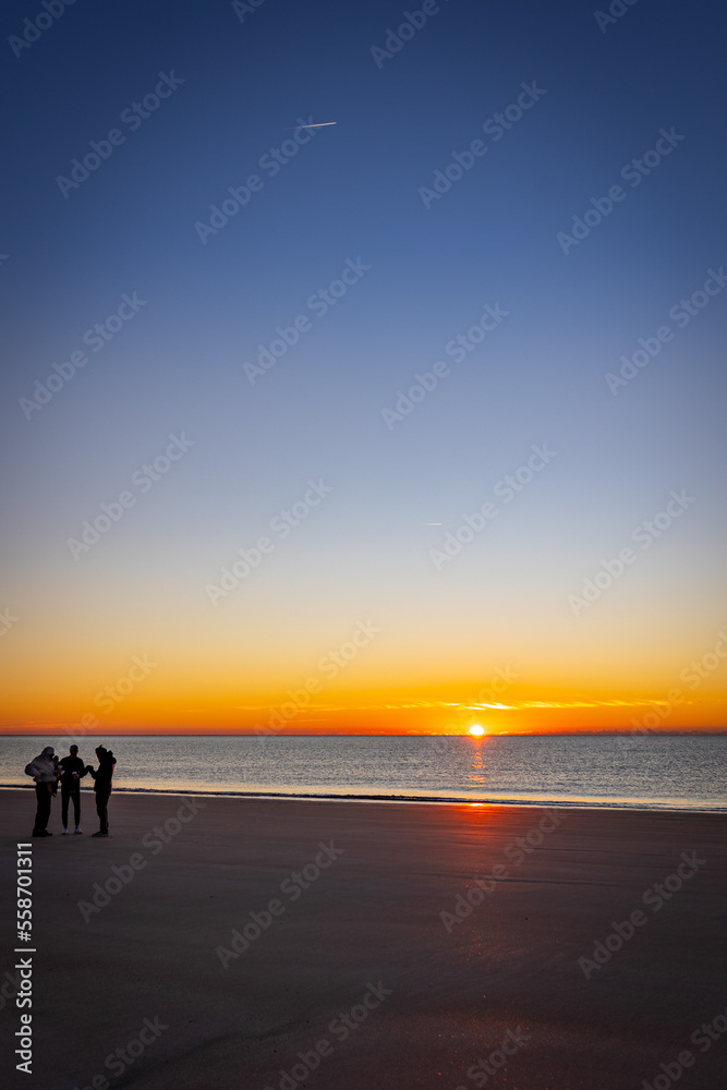 Silhouettes of people on the Hilton Head beach during dramatic sunrise