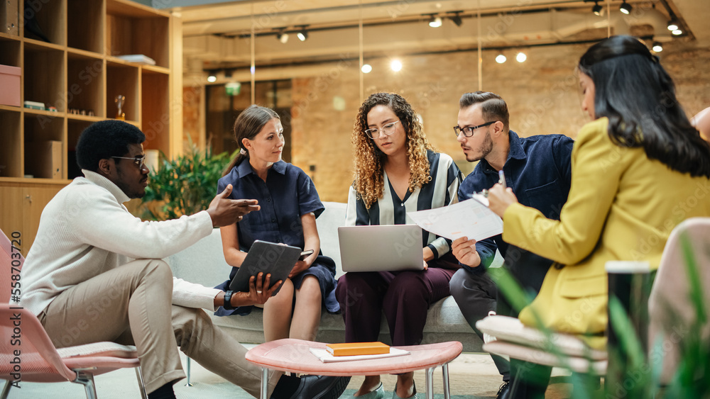 © Gorodenkoff - Group of People from Multiple Ethnicities Working on Problem Solving Using Notes, Laptop and Tablet in a Meeting Room at the Office. Teammates Giving Constructive Feedback on Eachother's Projects