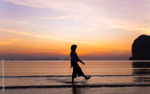 Silhouette beautiful Asian women is chilling on the beach with beautiful sunset