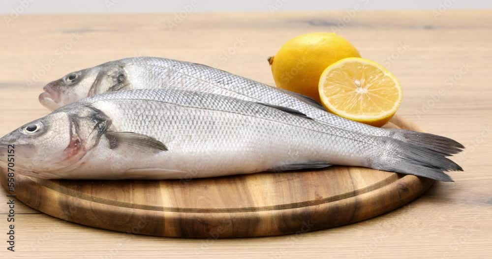 Raw fish with lemon lies on a wooden cutting board Raw fish with lemon lies on a wooden cutting board