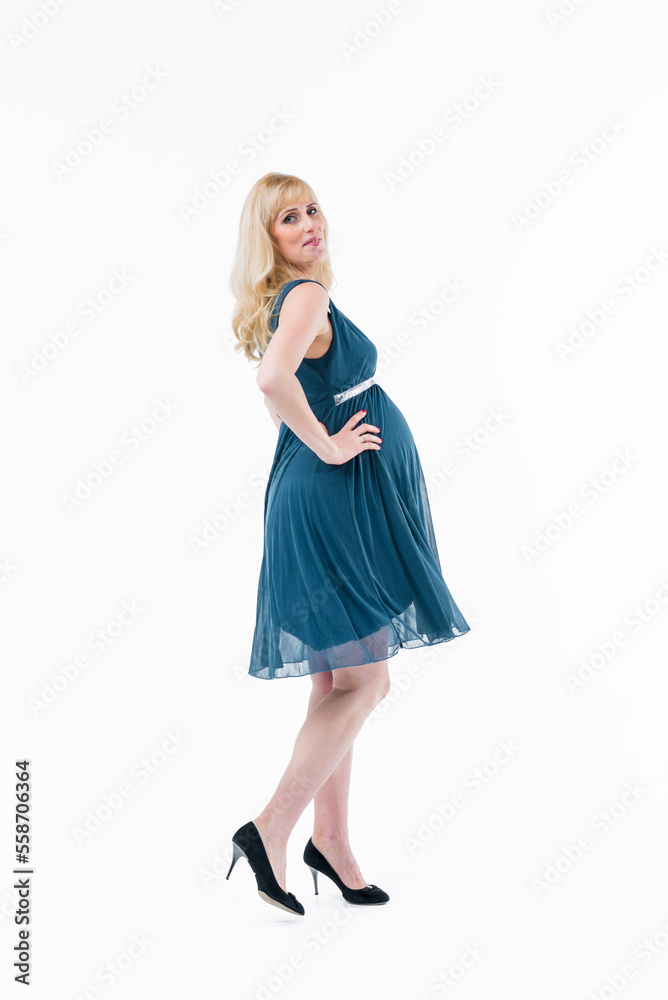 A beautiful pregnant woman in a turquoise dress hugs her stomach with her hands. Place for the text. White background. A beautiful pregnant woman in a turquoise dress hugs her stomach with her hands. Place for the text. White background.