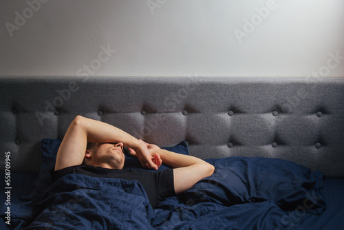Top view of a handsome young man sleeping comfortably on the bed at night in his bedroom. Sleep in different positions. Bachelor bedroom. Deep sleep.