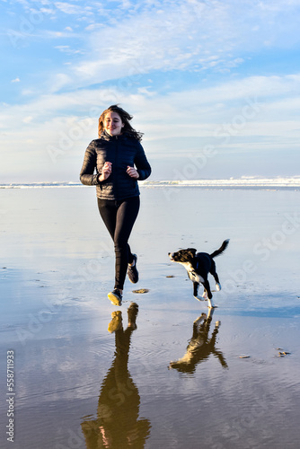 Young woman having fun with her puppy on vacation at the beach
