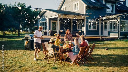 Group of Multiethnic Diverse People Having Fun, Communicating with Each Other and Eating at Outdoors Dinner. Family and Friends Gathered Outside Their Home on Warm Summer Day.