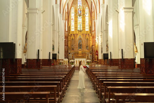 Asian Vietnamese woman praying in empty christian church with cross, architecture design. Religious beliefs. Catholic religion. Jesus worship. People lifestyle.