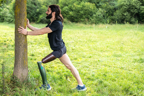 Disabled athlete amputee leg start his stretching session before running in the park outdoors