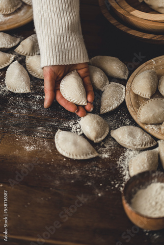 Pierogi in the making, being held in a womans hands photo