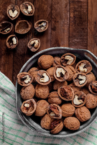 Bowl with dried organic walnuts on a wooden background.