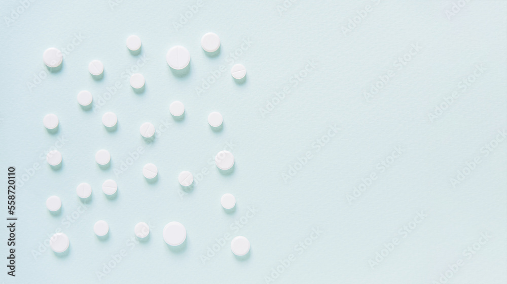 Scattered white pills on blue table. Mock up for special offers as advertising, web background or other ideas. Medical, pharmacy and healthcare concept. Copy space. Empty place for text or logo Scattered white pills on blue table. Mock up for special offers as advertising, web background or other ideas. Medical, pharmacy and healthcare concept. Copy space. Empty place for text or logo