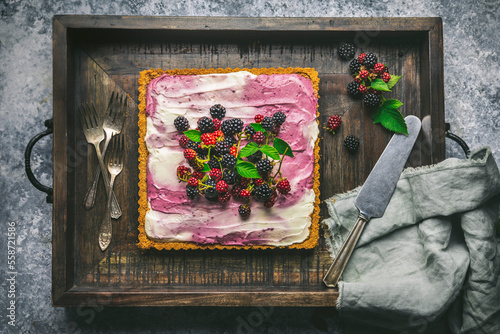 Blackberry cheesecake with berries on wooden tray with forks and knife photo
