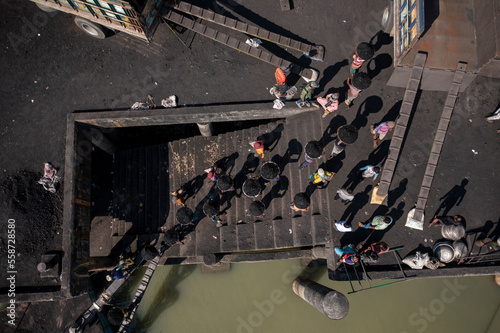 Aerial view of people working on boats along the riverbank unloading coal, Bhairab Upazila, Kishoreganj, Bangladesh. photo