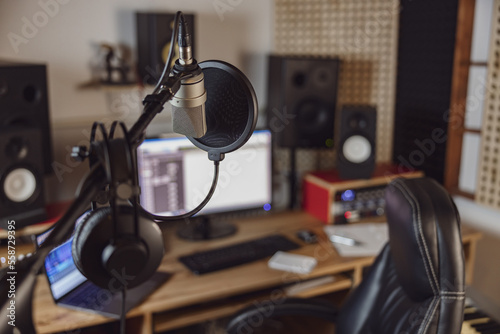 Focus on professional microphone and headphones in the blurred workplace for broadcasting and sound recording studio