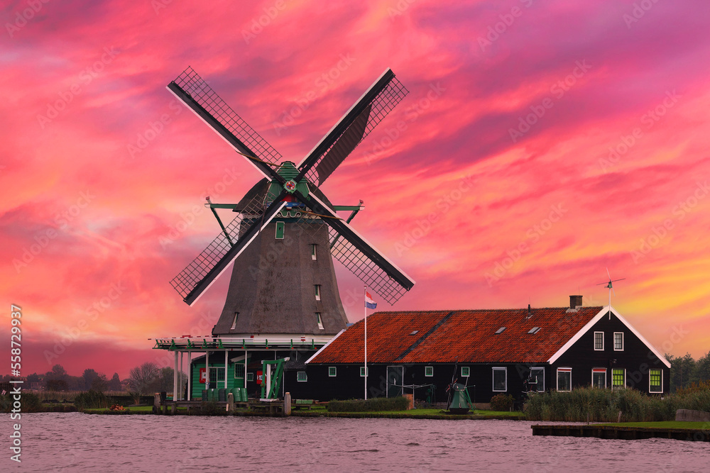 Dutch traditional wooden windmill on a red sunset background. Netherlands