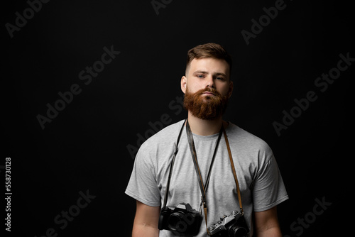 Film photography. Bearded photographer with a bunch of different vintage old film cameras. Close up portrait of man holding vintage camera.