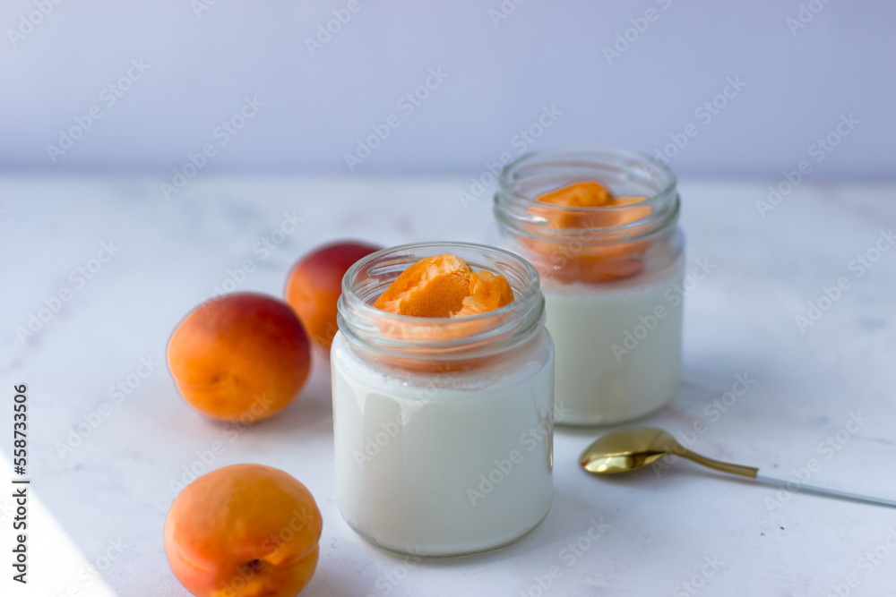 Homemade yogurt with juicy apricots. Yogurt on a white table Homemade yogurt with juicy apricots. Yogurt on a white table