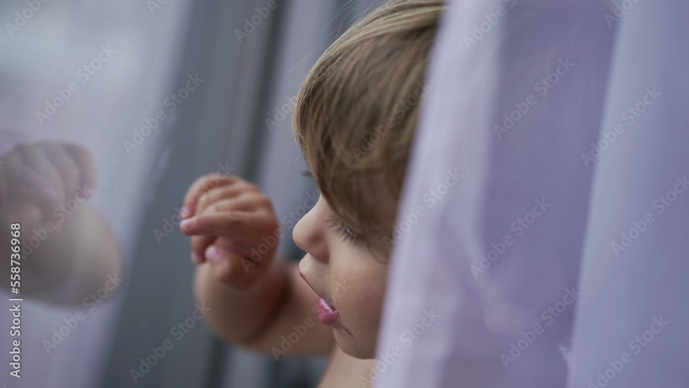 Obraz premium Child standing by window glass pointing with finger, toddler 2 year old baby