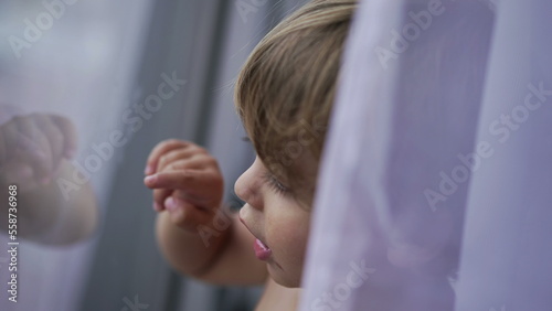 Child standing by window glass pointing with finger  toddler 2 year old baby