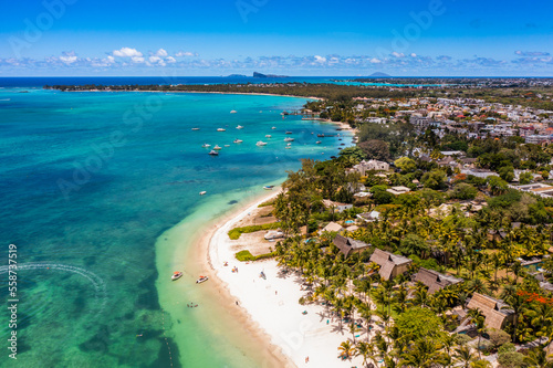 Mauritius - aerial landscape view along the coastline at Troy aux Biches Beach and Mont Choisy Beach in the background, with people walking on beach and boats swimming in the water of Indian Ocean 