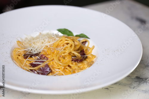 Pasta carbonara with bacon, cream and cheese on a white plate in a restaurant
