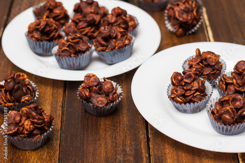 Chocolate cornflake cookies served on white plates. Chocolate cornflake cake in blue paper cupcake case
