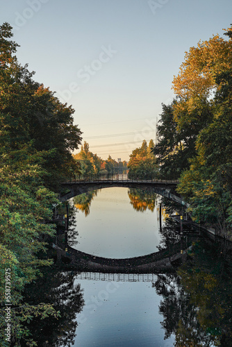 An old bridge over a canal with autumn forest left and right