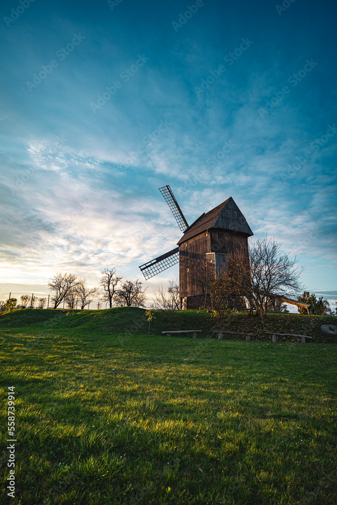 Old trestle windmill on a hill in the sunset
